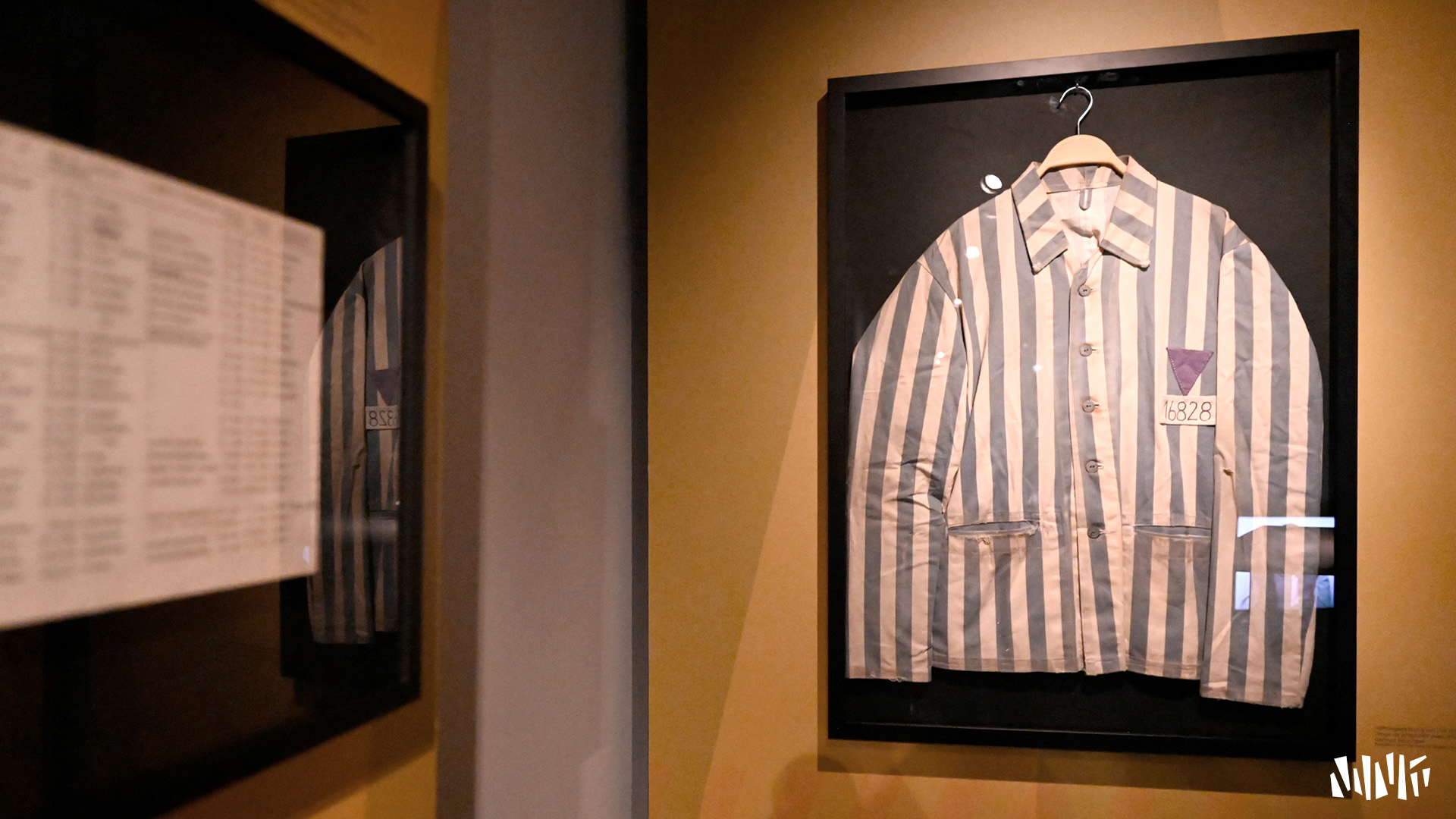 View of a wall with a frame containing a prisoner's shirt with blue and white vertical stripes